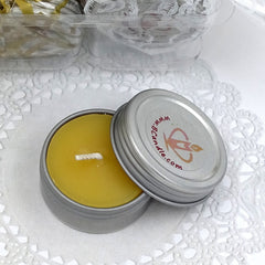 small candles in metal tins on a white doily with background.