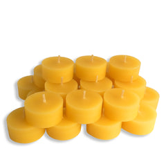 A pile of small round yellow tea light candles with visible wicks, arranged together on a plain white background.