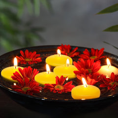 Floating candles and flowers on water with a blurred natural background