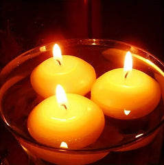 Three floating candles in a glass bowl with a dark background