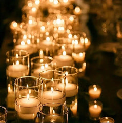Candlelit scene with numerous small candles in glass holders on a reflective surface.
