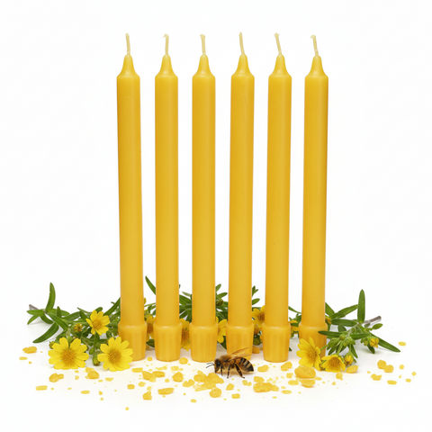 Six yellow taper candles standing upright on a white background, surrounded by yellow flowers, green leaves, and a small bee.