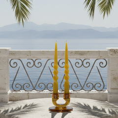 Decorative candle holder on a stone pedestal with ocean and palm trees in the background